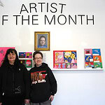 Two Women standing in front of a wall with four drawings